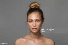 Closeup studio shot of a beautiful young woman with freckles skin posing against a grey background